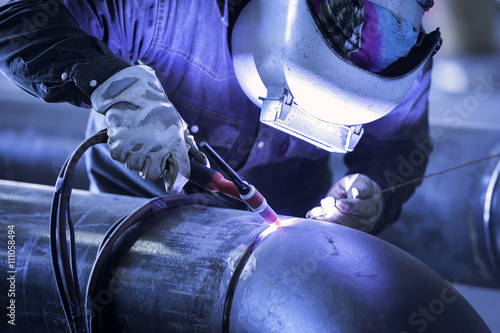 Fotótapéta Worker welding metal piping using tig welder