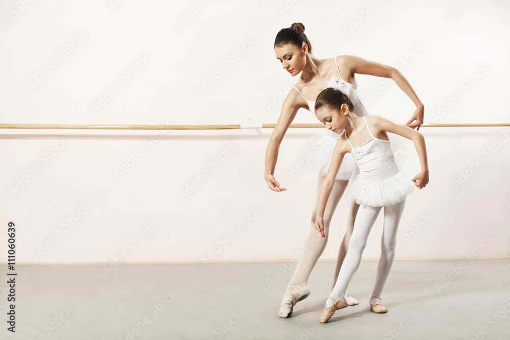 Naklejka premium Little ballerina dancing with ballet teacher in dance studio