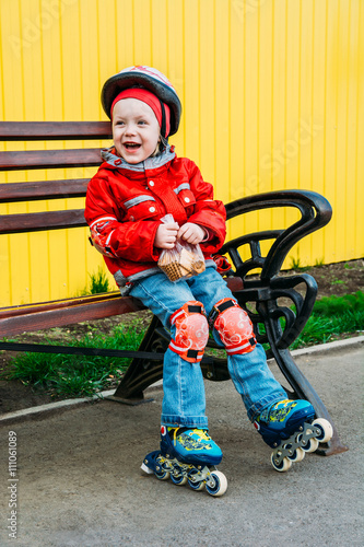 little girl in roller skates sitting on bench