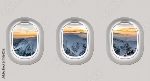 Looking out the windows of a plane to the winter mountains