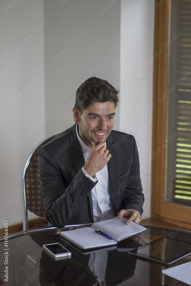 Young worker man smiling and touching his chin during a business meeting Young worker man smiling and touching his chin during a business meeting