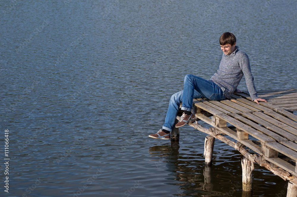Man sitting on the pier of a lake Man sitting on the pier of a lake