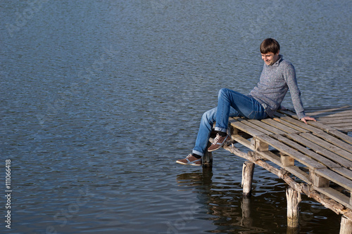 Man sitting on the pier of a lake