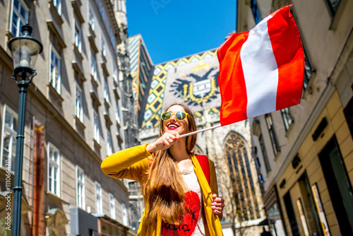 Photography Young smiling woman holding austrian flag with the roof eagle emblem on the back