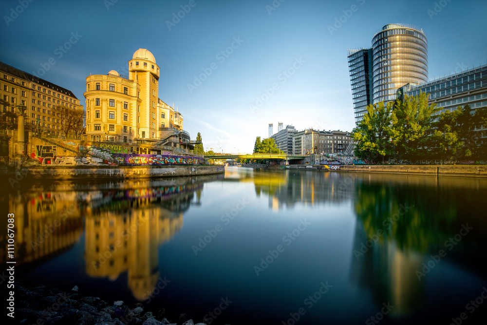 Vienna cityscape with modern Uniqa and Urania tower on the water channel in the morning. Long exposure image technic with glossy water and reflection