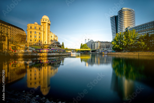 Vienna cityscape with modern Uniqa and Urania tower on the water channel in the morning. Long exposure image technic with glossy water and reflection