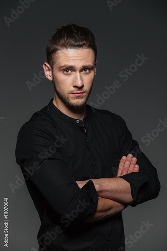Portrait of attractive confident young man standing with arms crossed