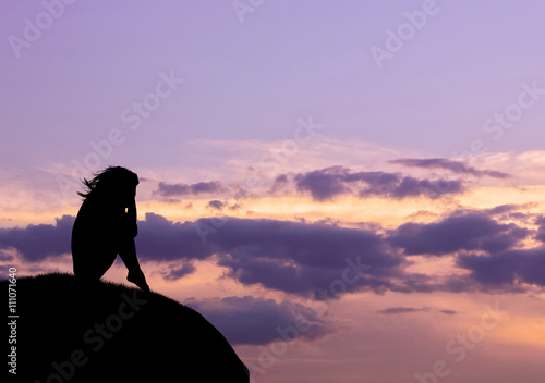Silhouette of a lonely sad woman on top of a hill