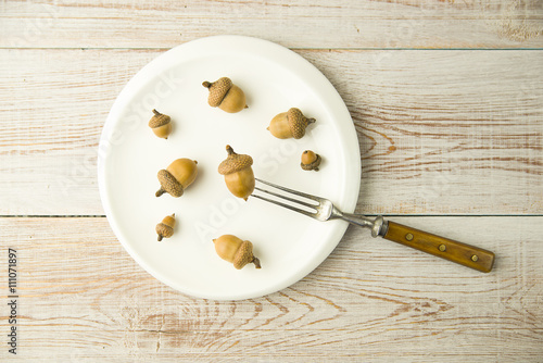 Foto Acorns in a plate and fork on the table