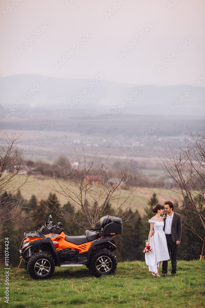 Obraz premium Happy beautiful couple near four-wheeler ATV in foggy nature. Smiling looking into distance