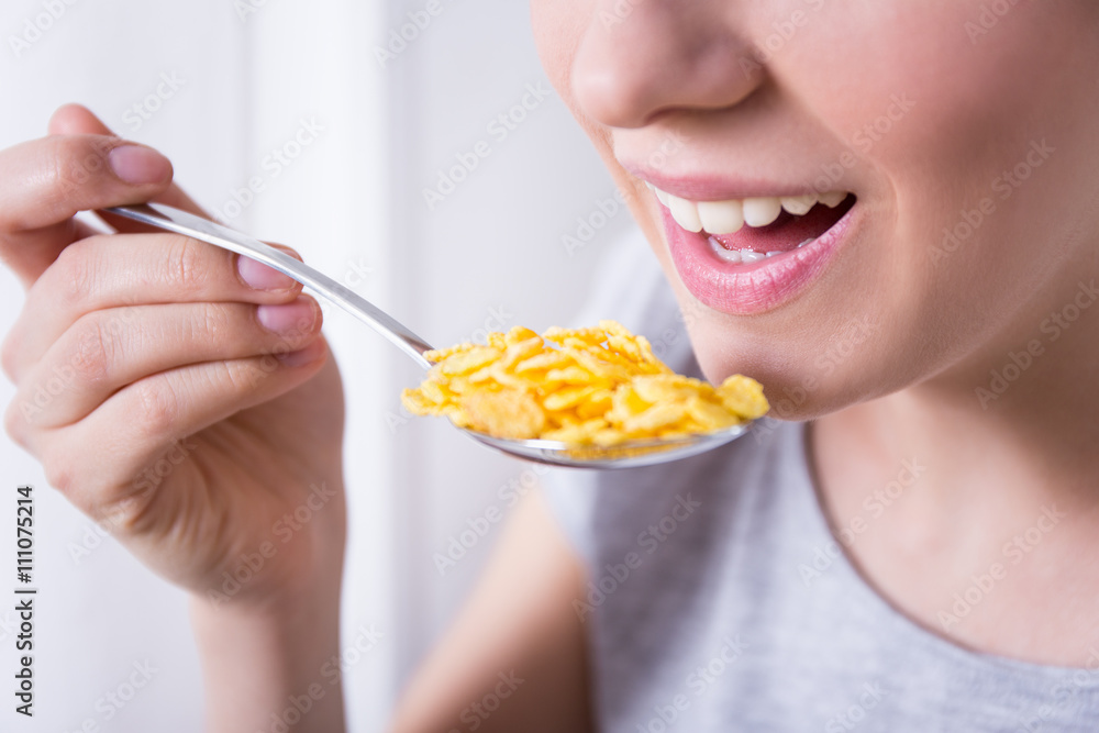 young woman having breakfast with corn flakes young woman having breakfast with corn flakes