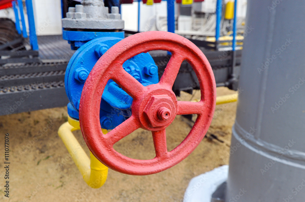 Red faucet with steel pipe in natural gas compressor station in summer day