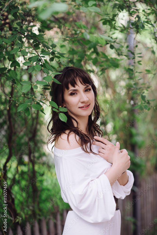 Portrait of a beautiful brunette woman outdoors in a white dress. Close-up portrait. Summer outdoor portrait Portrait of a beautiful brunette woman outdoors in a white dress. Close-up portrait. Summer outdoor portrait