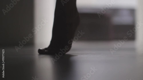 Silhouette of the female feet  dancing in the doorway in the dark. Shadows and reflections. Woman in the doorway.Handheld close up shot.
