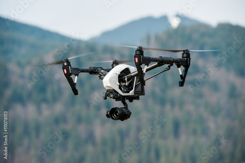 drone with high resolution digital camera/White drone with digital camera flying in sky over mountain