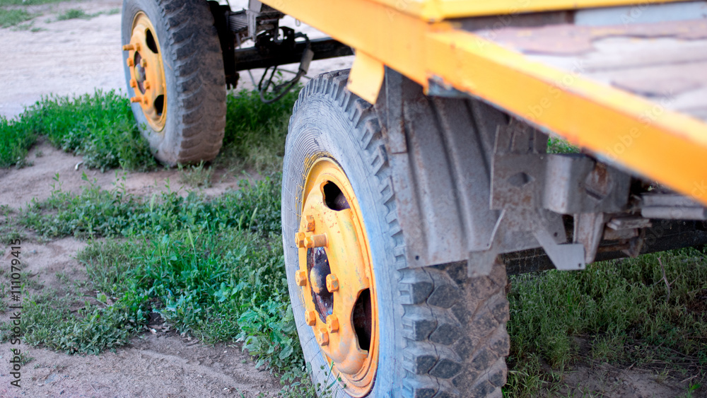 The old truck tire painted in bright yellow color in rural area closeup, selective focus The old truck tire painted in bright yellow color in rural area closeup, selective focus