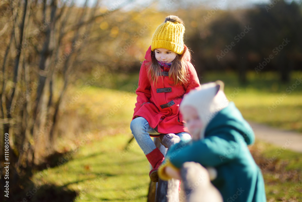 Two little sisters having fun together in beautiful autumn park Two little sisters having fun together in beautiful autumn park