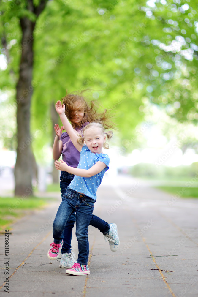 Two adorable little sisters laughing and hugging each other Two adorable little sisters laughing and hugging each other