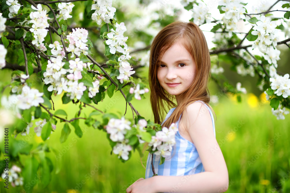 Adorable little girl in blooming apple tree garden on spring day Adorable little girl in blooming apple tree garden on spring day