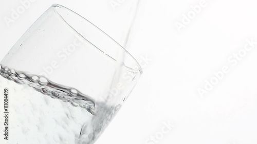 Loopable cinemagraph video. Close Up of water pourin into a glass.  photo