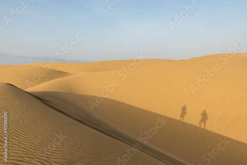 Shadow of Couple in sand dunes in desert