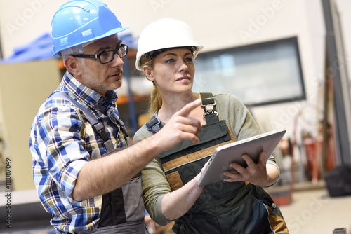 Engineers in warehouse checking stock with tablet