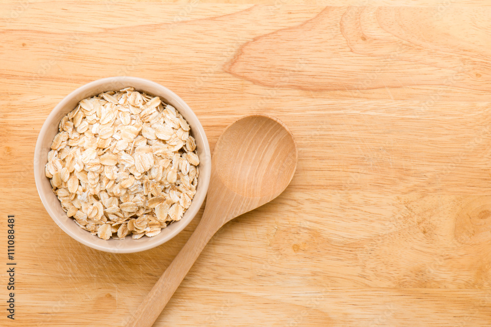Rolled oats in a cup and wooden spoon on a wooden background Rolled oats in a cup and wooden spoon on a wooden background
