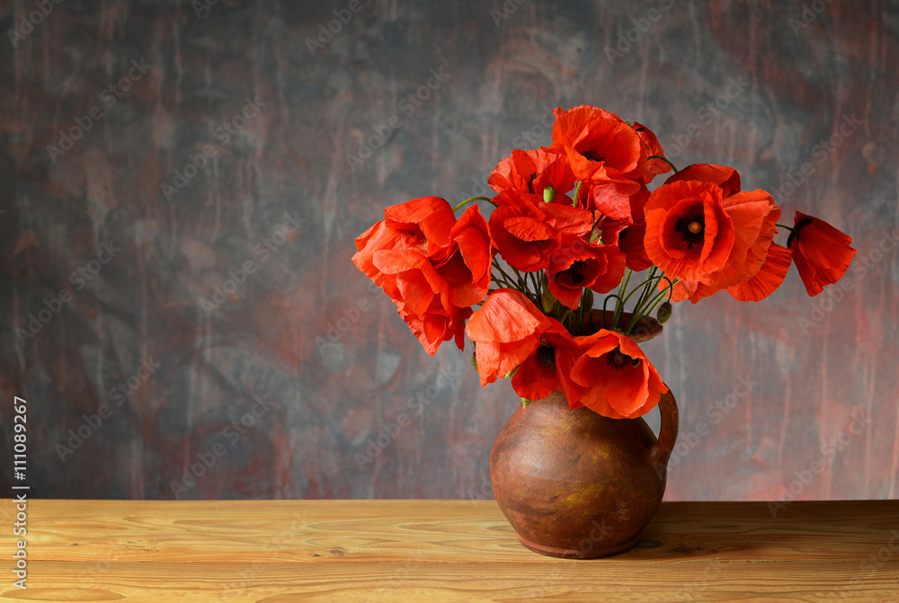 Fototapeta premium Red poppies in a ceramic vase on a wooden table