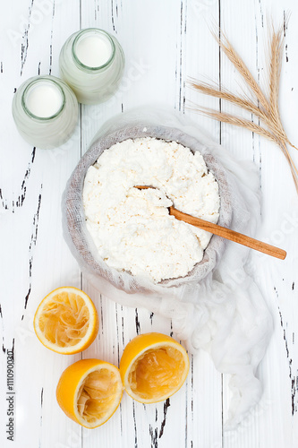 Soft homemade fresh ricotta cottage cheese made from milk, draining on muslin cloth. Tzfat cheese with wheat grains. Symbols of judaic holiday Shavuot.