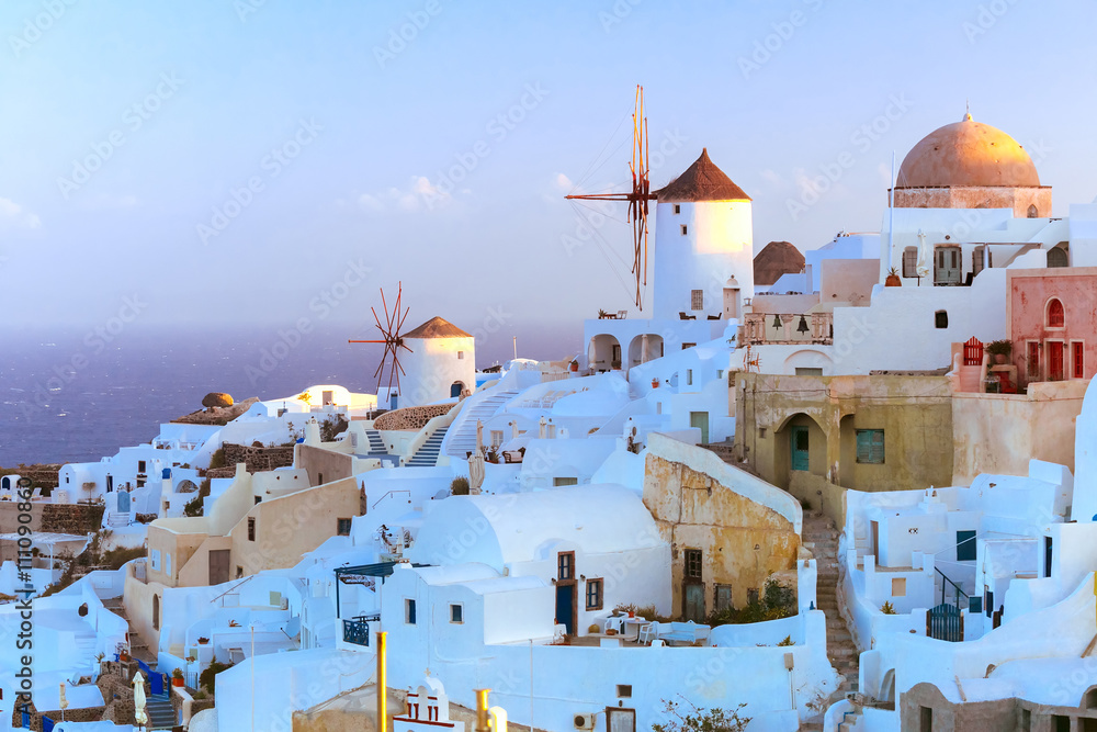 Picturesque famous view, Old Town of Oia or Ia on the island Santorini, white houses and windmills at dawn, Greece