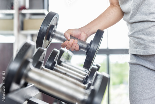 strong woman's hand takes a heavy dumbbell in gym