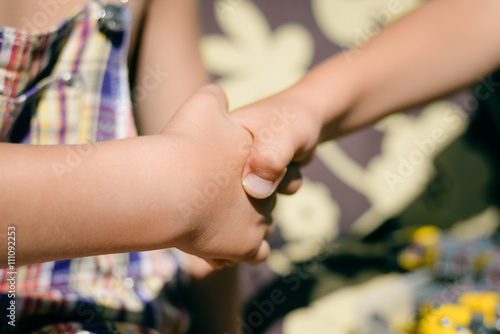 Kids handshake closeup on sunny outdoors background