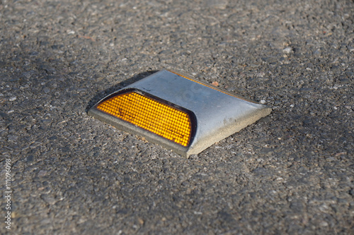 Obraz na plátně Metal road stud with yellow reflector on asphalt road