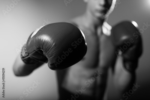 Black and white photography of young boxer fighter over grey background, closeup 