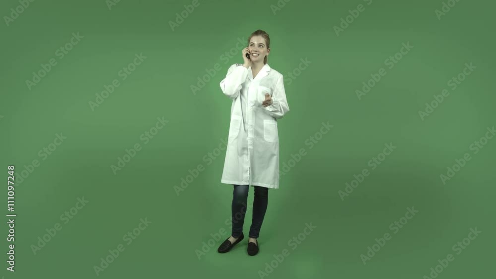 attractive caucasian girl with lab coat isolated on green happy talking with cell phone attractive caucasian girl with lab coat isolated on green happy talking with cell phone
