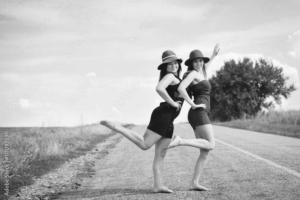 Black white photography of two beautiful elegant girls in hats on a sunny summer day background outdoors Black white photography of two beautiful elegant girls in hats on a sunny summer day background outdoors