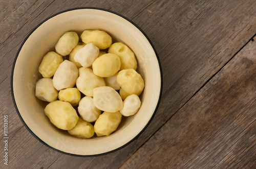 peeled raw potatoes in an enamel pot on the old boards. top view, close-up