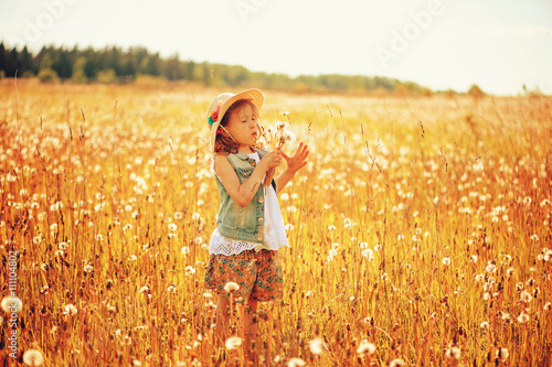 happy child girl walking on summer meadow with dangelions. Rural country style scene, outdoor activities. Cozy lifestyle. photo