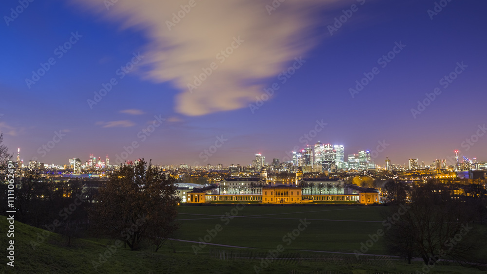 Skyscrapers of Canary Wharf and London's National Maritime Museum taken from Greenwich park at dusk - London, UK