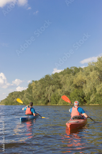 Two guys travel the river on a kayaking in the summer.