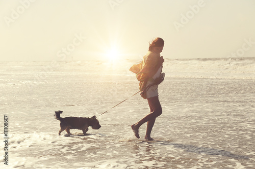 jolie femme senior active à la plage promenant son chien photo