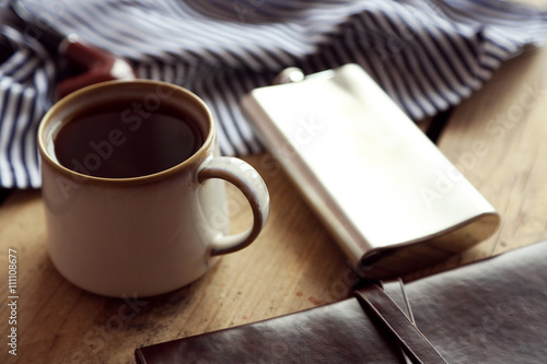 Cup of strong coffee with a flask on a wooden table, close up