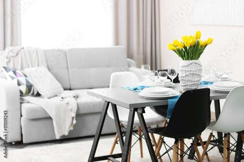 Dining room interior with sofa and table served for dinner