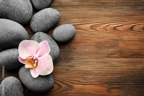 Spa stones and orchid flower on wooden background