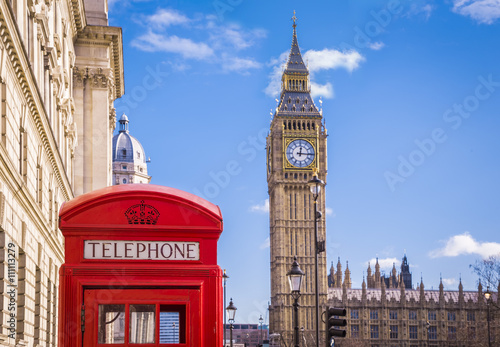 Traditional red british telephone box and Big Ben at Parliament Square with blue sky and clouds - London, UK