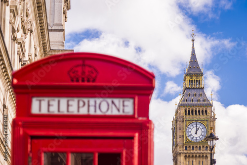Traditional red british telephone box and Big Ben at the background with blue sky and clouds - London  UK