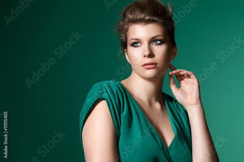 Portrait of a beautiful full girl in a green dress on a green background