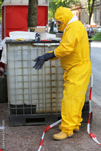 Arbeiter mit gelbem Schutzanzug vor IBC photo