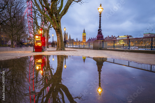 London, UK - Reflections of the The Big Ben and Houses of Parliament taken from South Bank of River Thames early in the morning with trees and clear blue sky photo