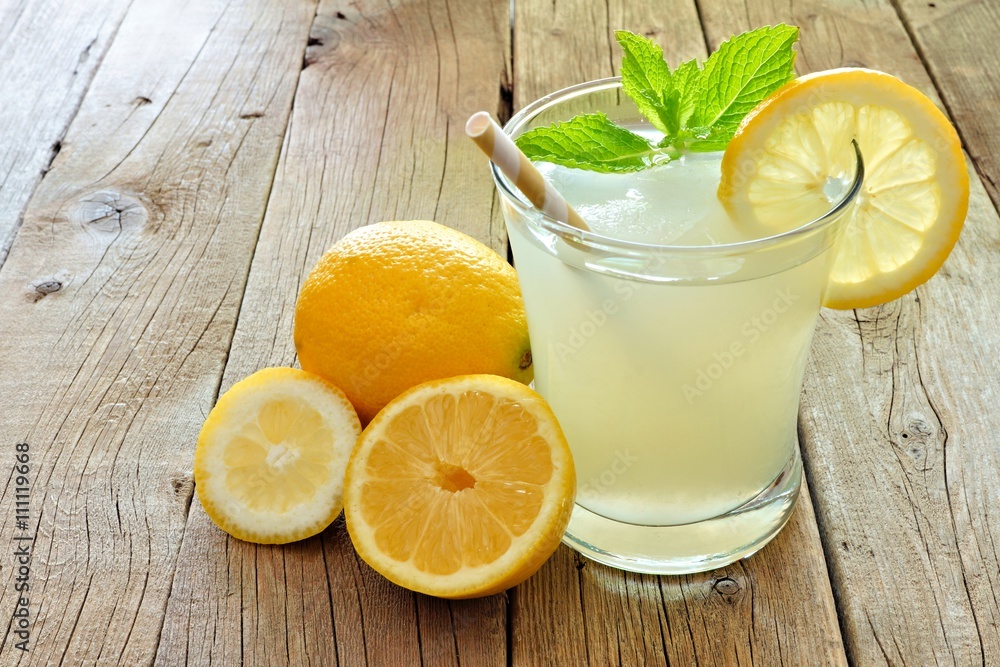 Glass of cold lemonade with lemon slices and mint on a rustic wood background Glass of cold lemonade with lemon slices and mint on a rustic wood background